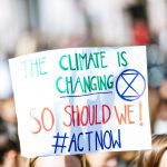 Bild på en skylt där det står "The climate is changing so should we! Act now!