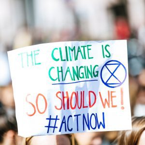Bild på en skylt där det står "The climate is changing so should we! Act now!