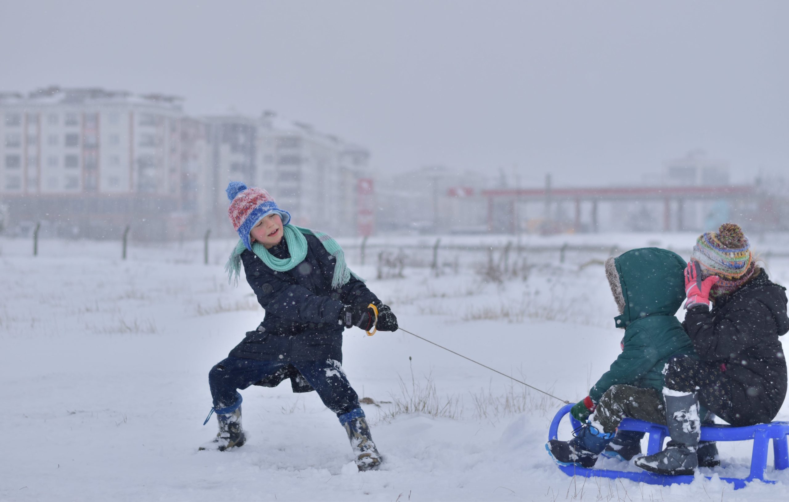 Barn leker med kälke i snön.