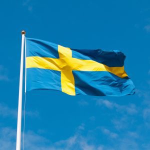 Foto på Sveriges flagga med blå himmel som bakgrund