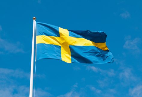 Foto på Sveriges flagga med blå himmel som bakgrund