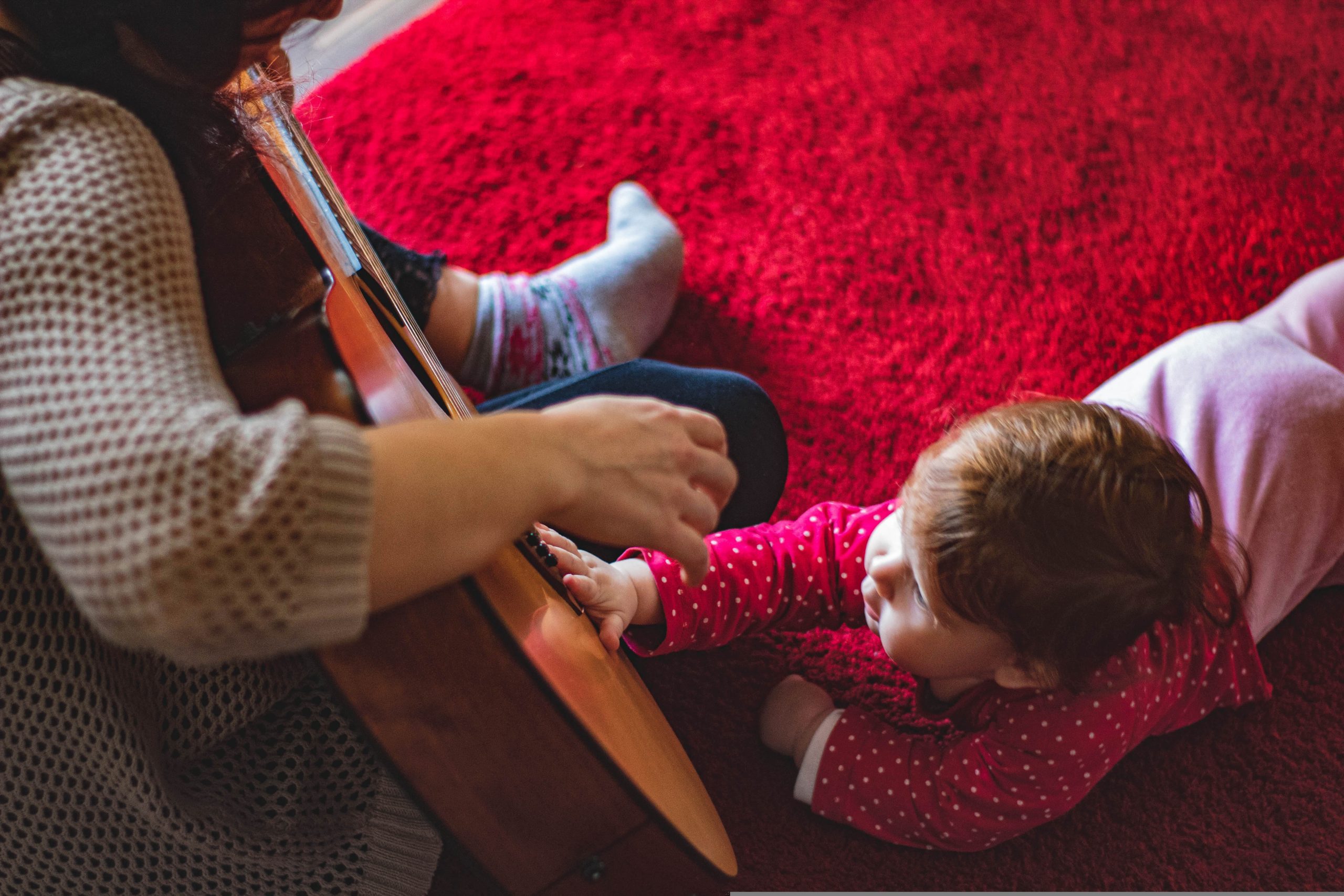 vuxen som spelar gitarr sjunger för småbarn spädbarn bebis