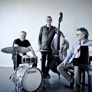 Bild på de tre medlemmarna i bandet Trio X som står vid sina instrumment