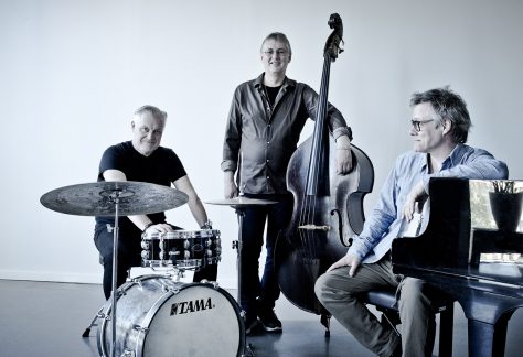 Bild på de tre medlemmarna i bandet Trio X som står vid sina instrumment