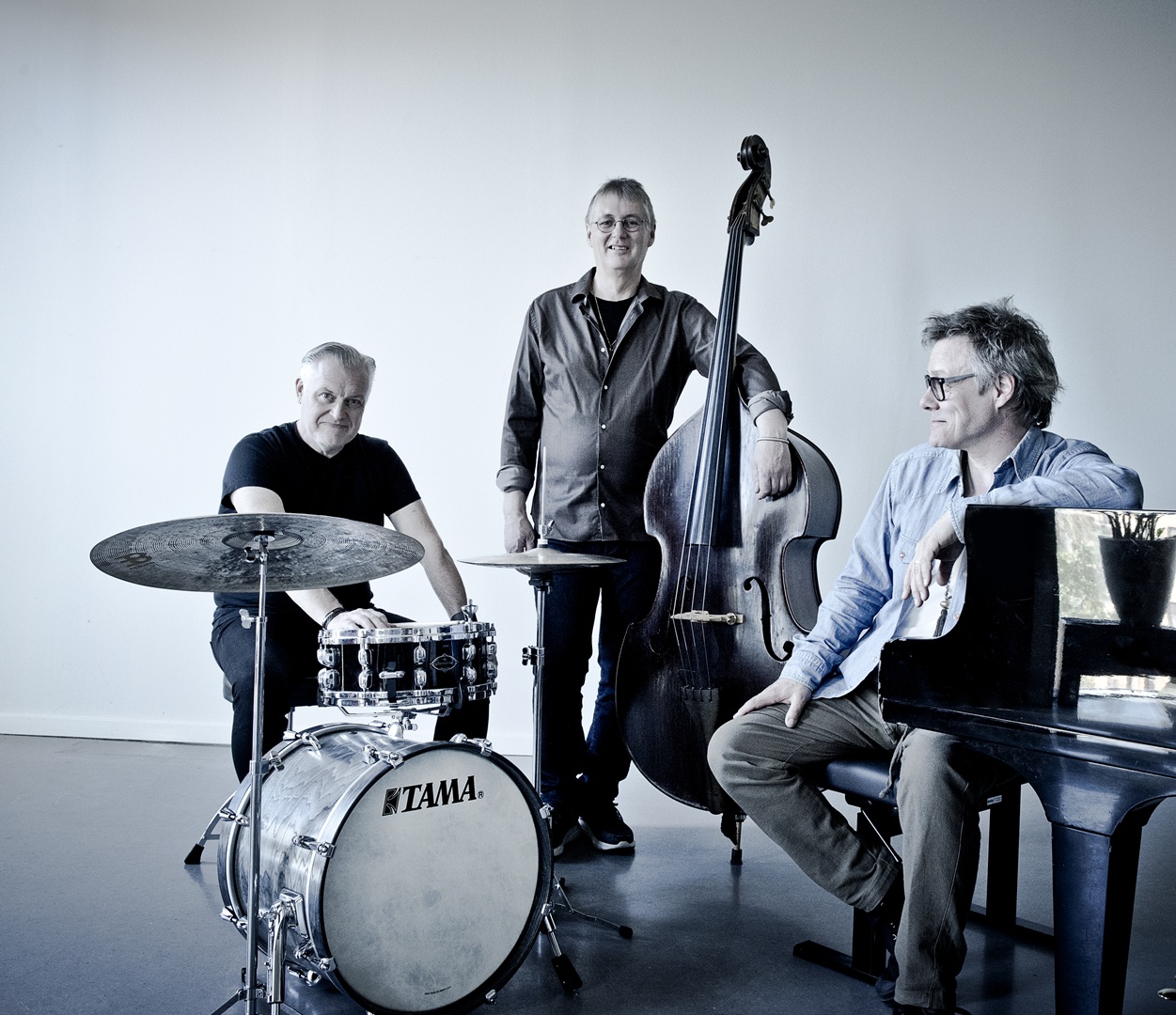 Bild på de tre medlemmarna i bandet Trio X som står vid sina instrumment