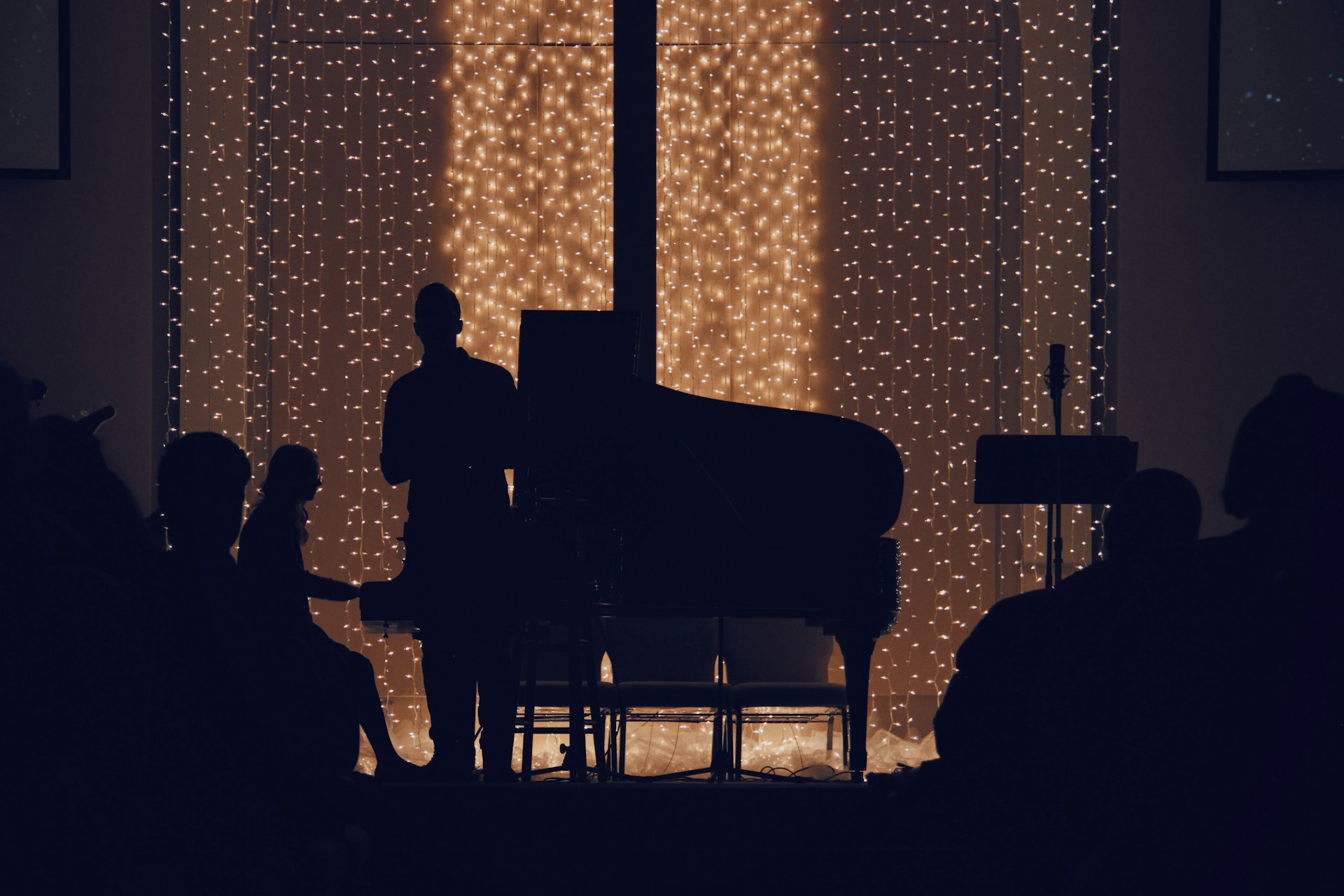 En man som spelar piano på en konsert i ett mörkt rum.