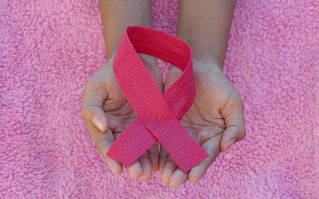 Ett stort rosa band i ett par händer, för bröstcancer