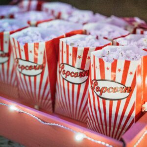 Massa rödvita popcorn bägare med popcorn i på en bricka.