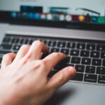 Bild på en hand på ett tangentbord på en laptop.