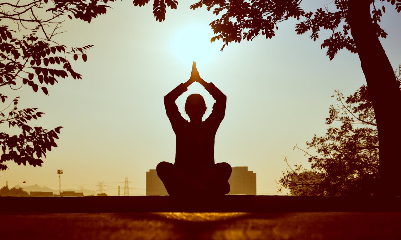 Bild på en person som mediterar genom yoga ute i naturen. Yoga med Nanna