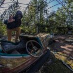 Man i gasmask på förfallet tivoli. In the Zone of Alienation