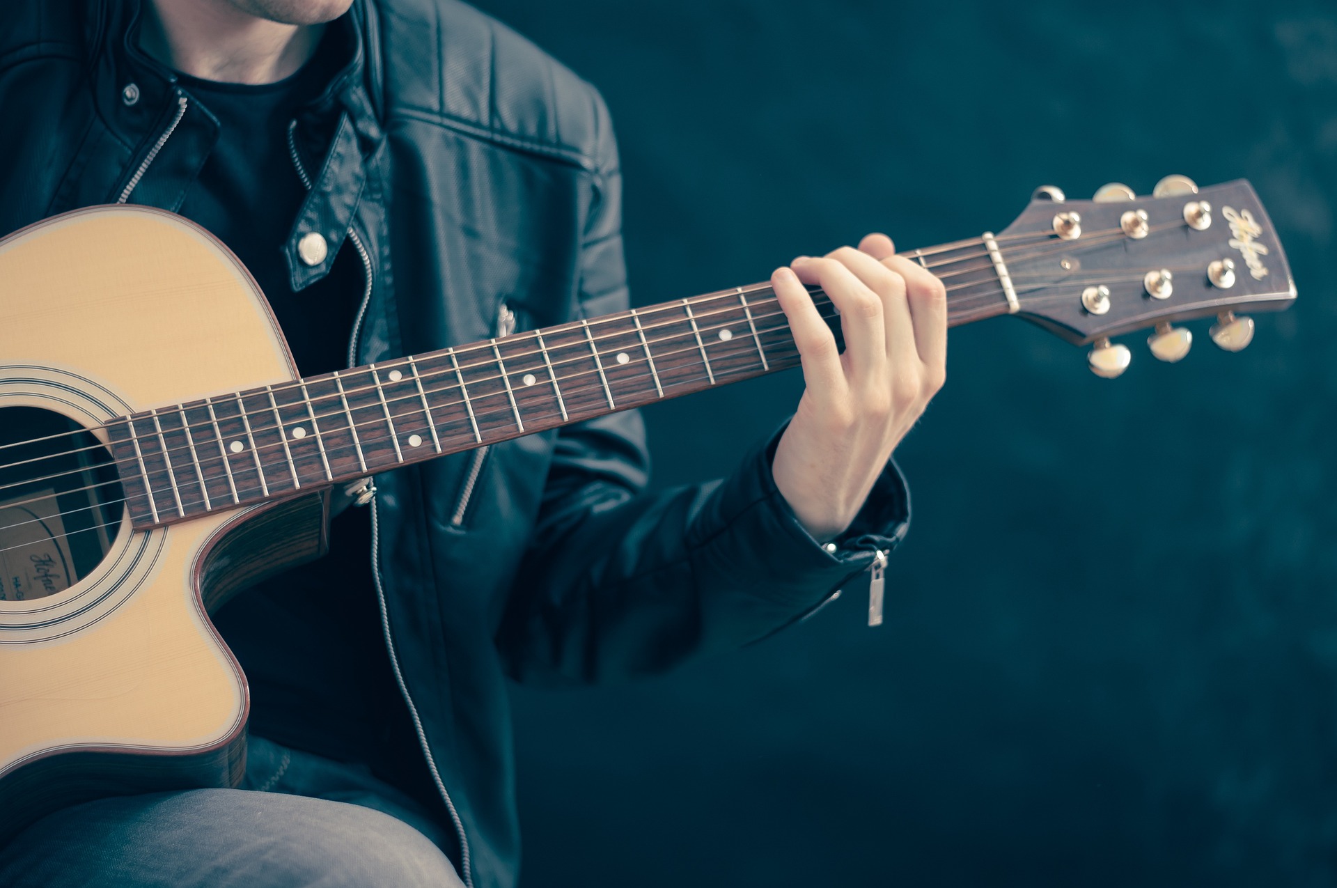 Foto på person som spelar akustiskt gitarr.