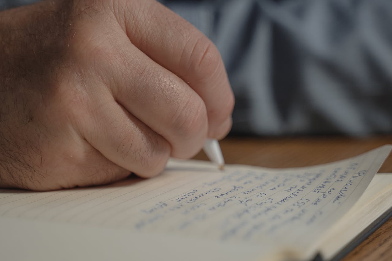 En hand som håller i en penna och skriver.