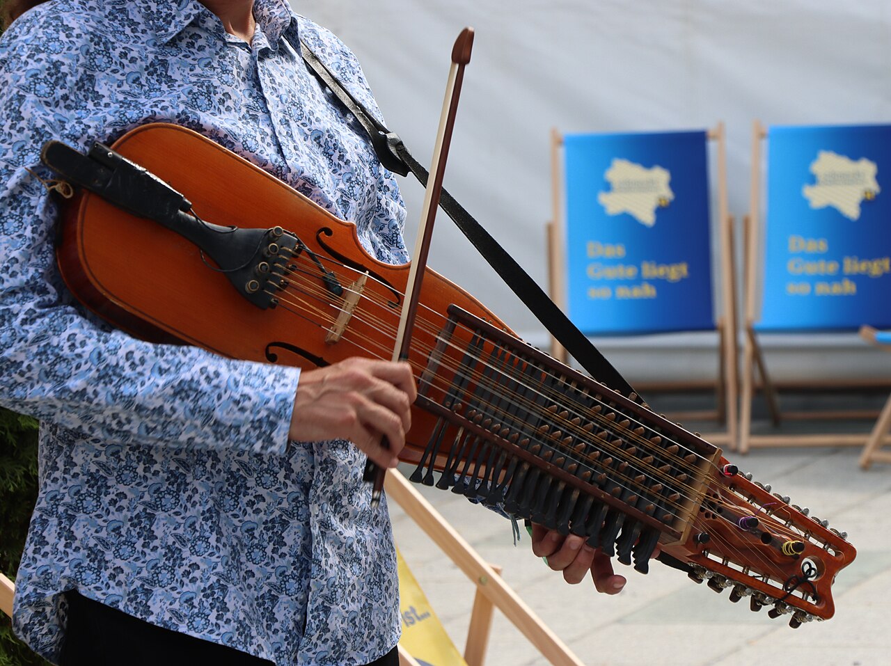 Bild på person i skjorta som spelar nyckelharpa.