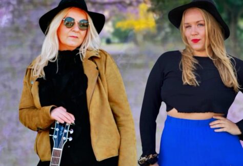 Nathalie och Katarina med svarta hattar och en med solglasögon och gitarr.
