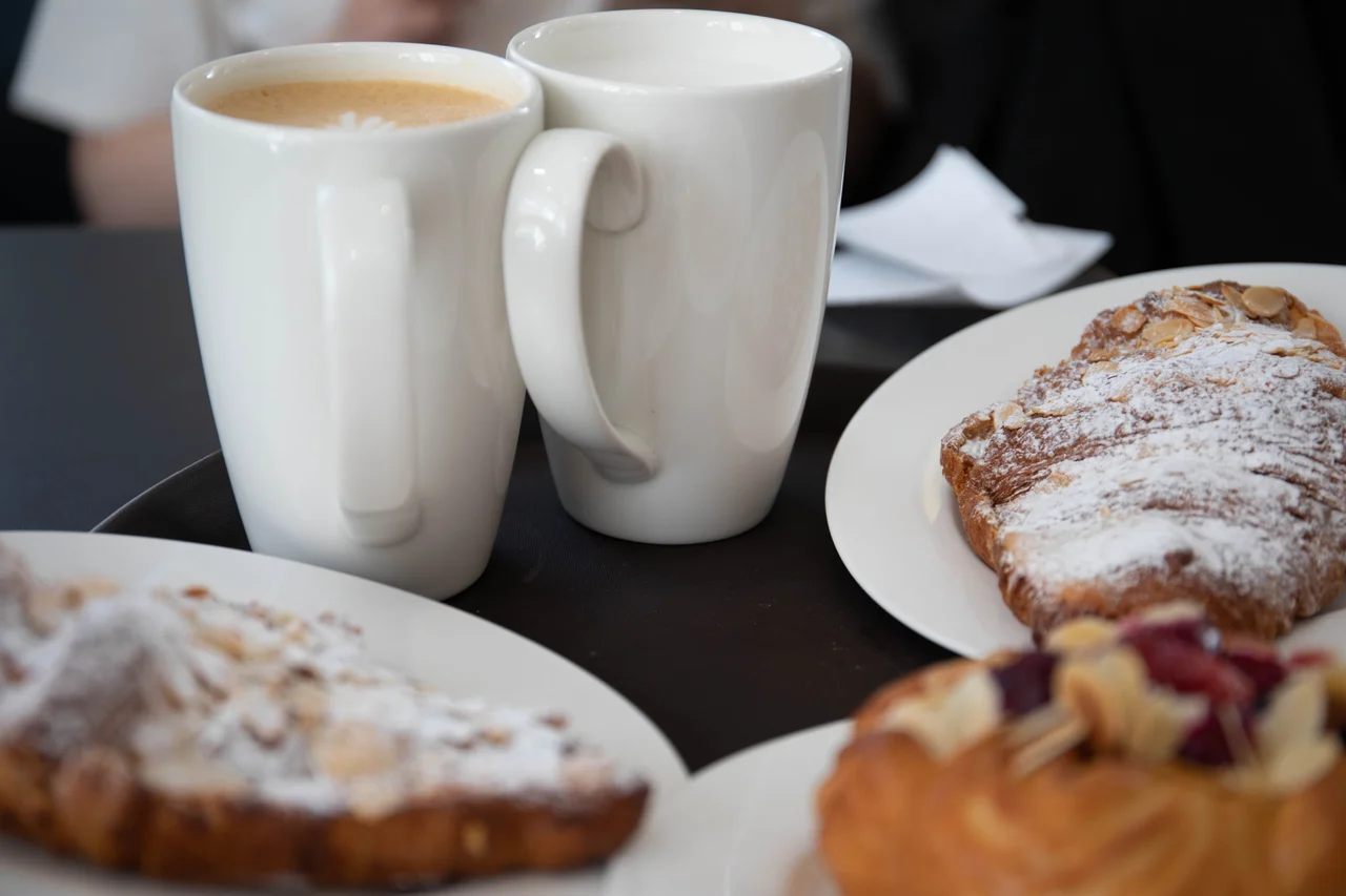 Bild på två kaffekoppar och bullar på ett bord.