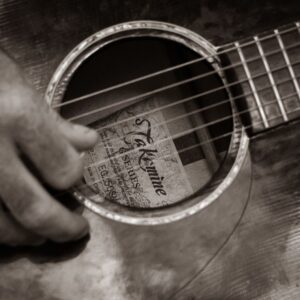 Närbild på en guitar med fokus på gitarrspelande hand
