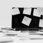 Bild på en dator som har massa post-it-lappar på sig, en där det står "Help" på.