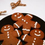 Bild på tre pepparkaksgubbar med glasyr på en svart tallrik.