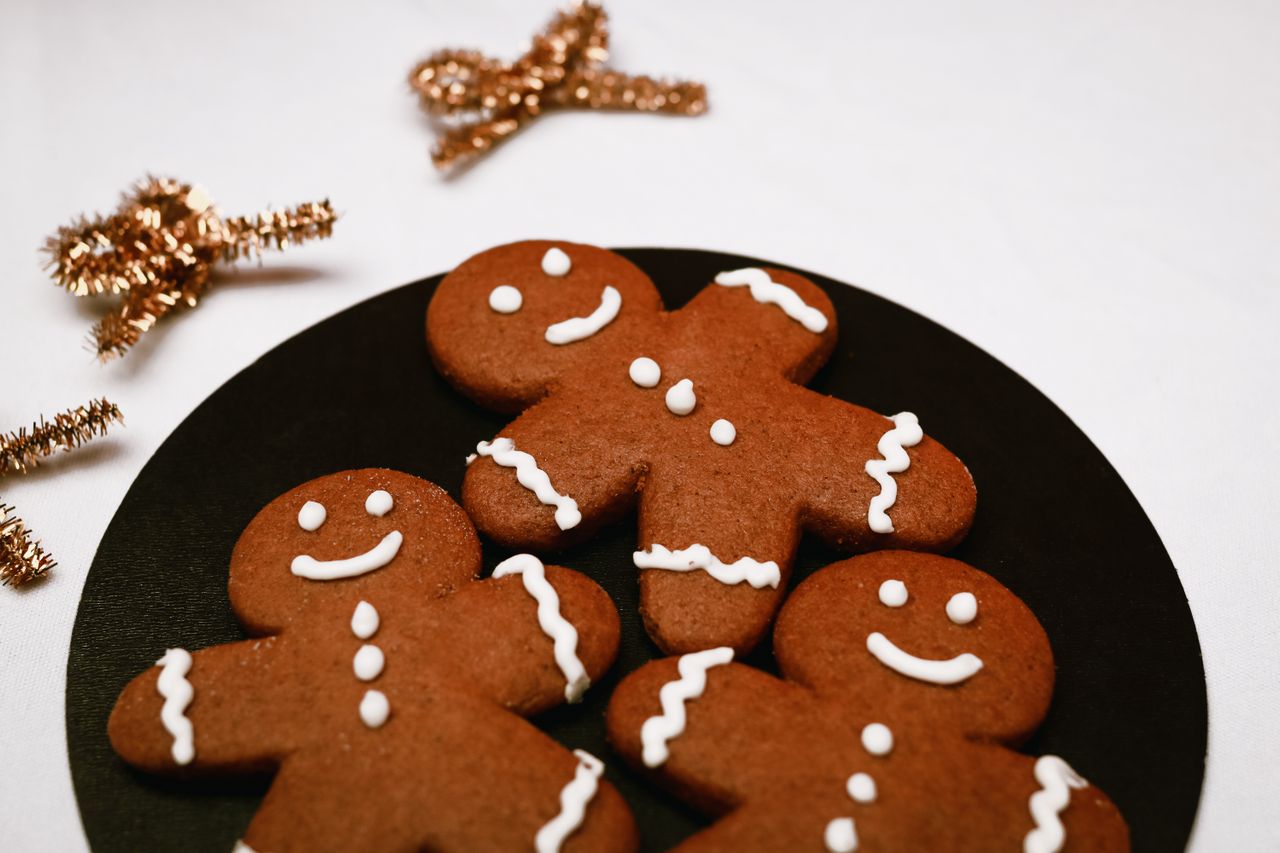 Bild på tre pepparkaksgubbar med glasyr på en svart tallrik.