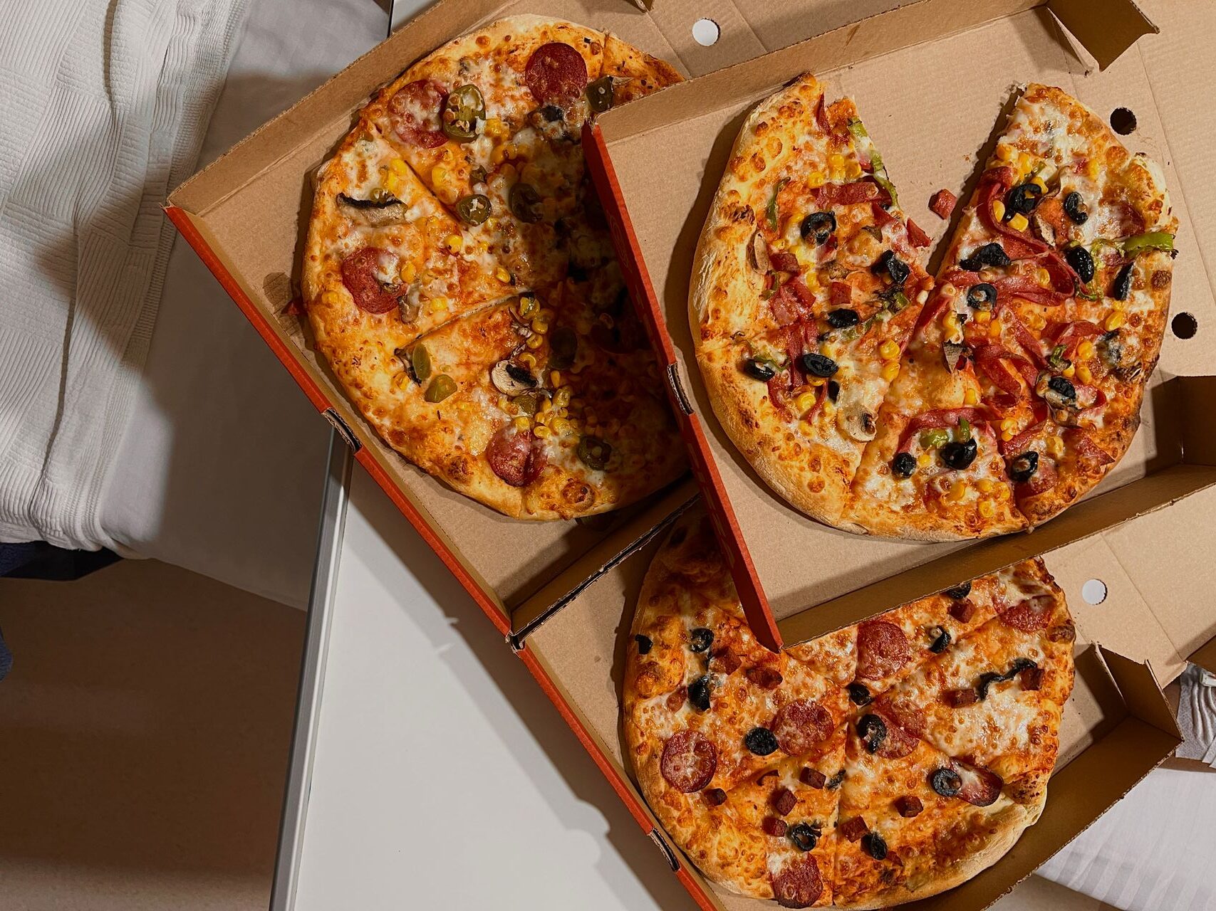 Bild på tre pizzor i öppna pizzakartonger.