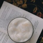 En skummig dryck i en kopp som är placerad på en öppen bok.