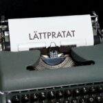 Bild på en gammal skrivmaskin med ett papper i, på pappret står det "lättpratat" med stora bokstäver.