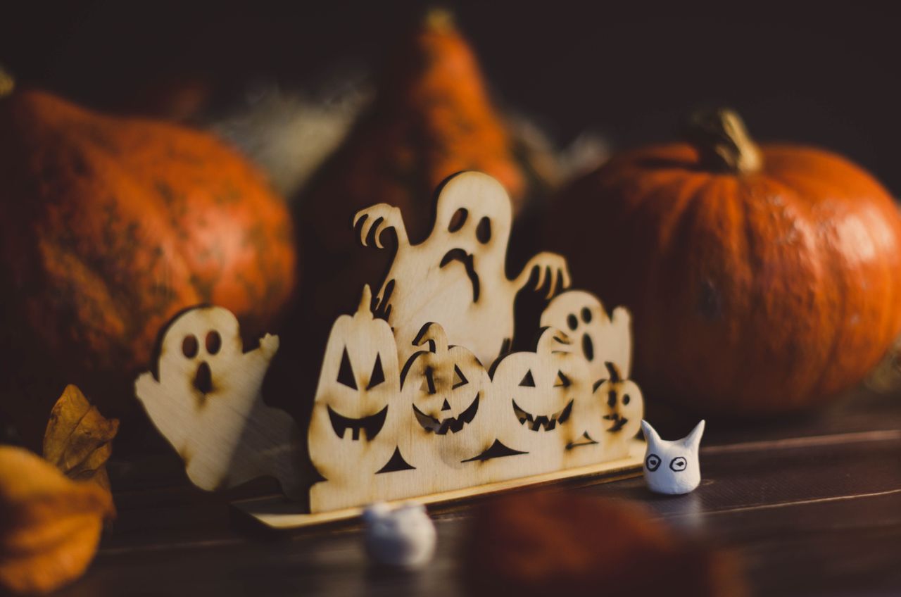 En festlig Halloween-inspirerad utsmyckning med träspöken och pumpor.