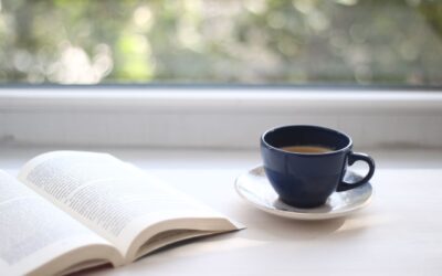 Bild på en öppen bok och en kaffekopp bredvid på ett bord.
