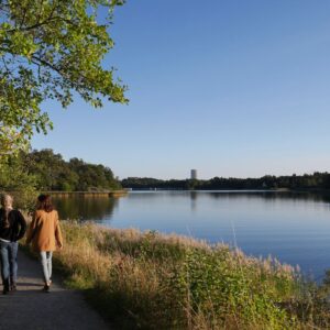 Par som promenerar en vacker solig dag längs en sjö