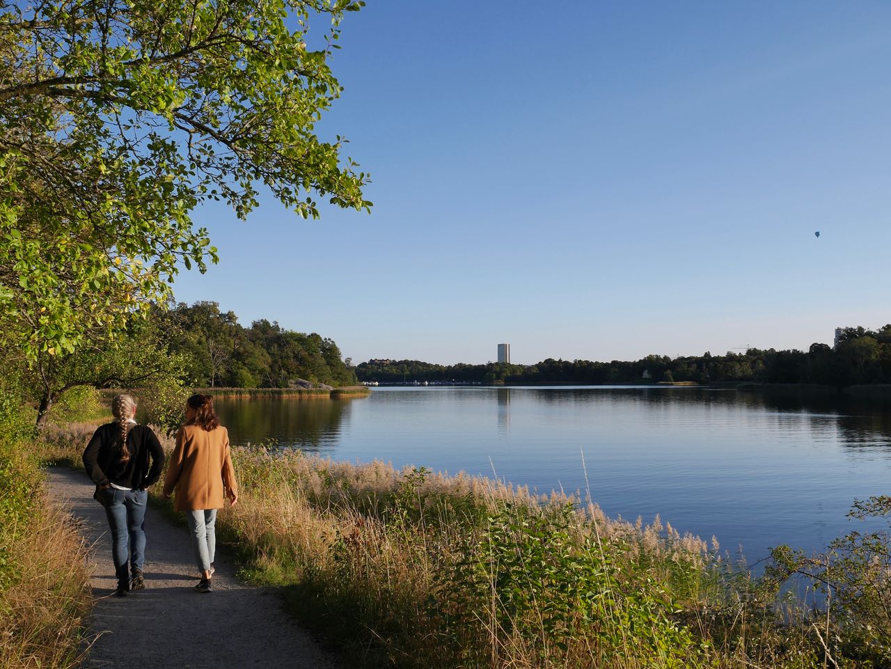 Par som promenerar en vacker solig dag längs en sjö