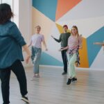 En grupp unga vuxna som deltar i en danslektion i en färgglad studiomiljö