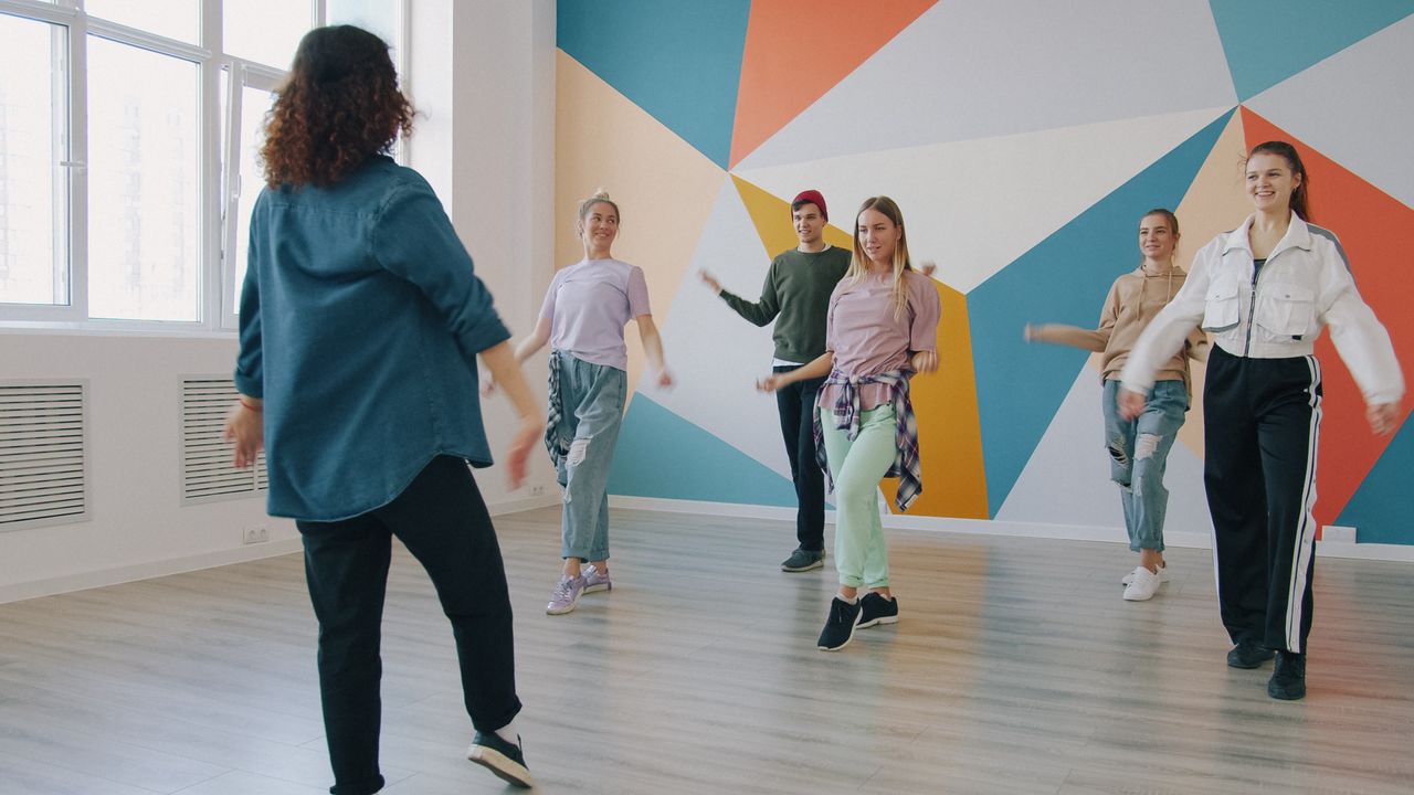 En grupp unga vuxna som deltar i en danslektion i en färgglad studiomiljö