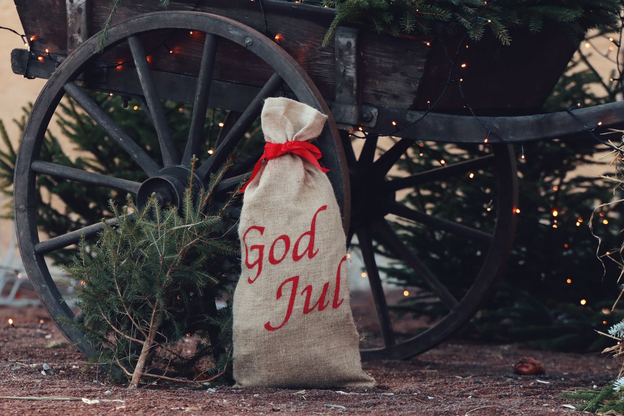 Bild på en julsäck som det står "God jul" på, den står lutat mot en vagn och man ser en gran i bakgrunden.
