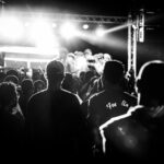 Konsertpublik tittar mot upplyst scen. Svartvit bild