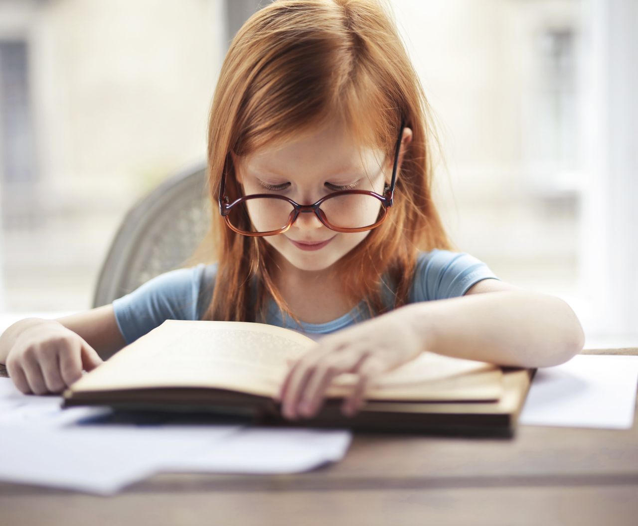Flicka i 5 -års åldern som läser en bok.