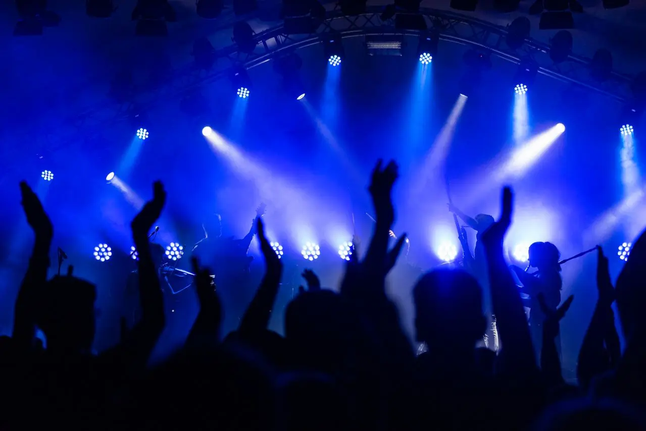 Dynamisk konsertscen med en jublande publik och livligt blått ljus.