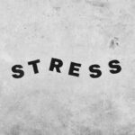 En grå bakgrund med ordet "stress" i svart på.