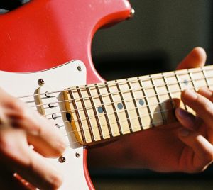 Närbild av händer som spelar på en elgitarr.
