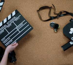 Bild på två händer som håller i en filmklappa och annat filmmaterial.