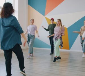En grupp unga vuxna som deltar i en danslektion i en färgglad studiomiljö
