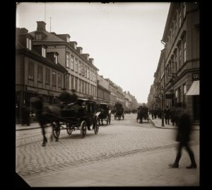 En AI-genererad bild som ska efterlikna ett fotografi av en stad med folk på gatan från början av 1900-talet.